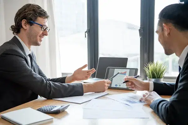 Financial adviser reviewing investment charts on a tablet with a client