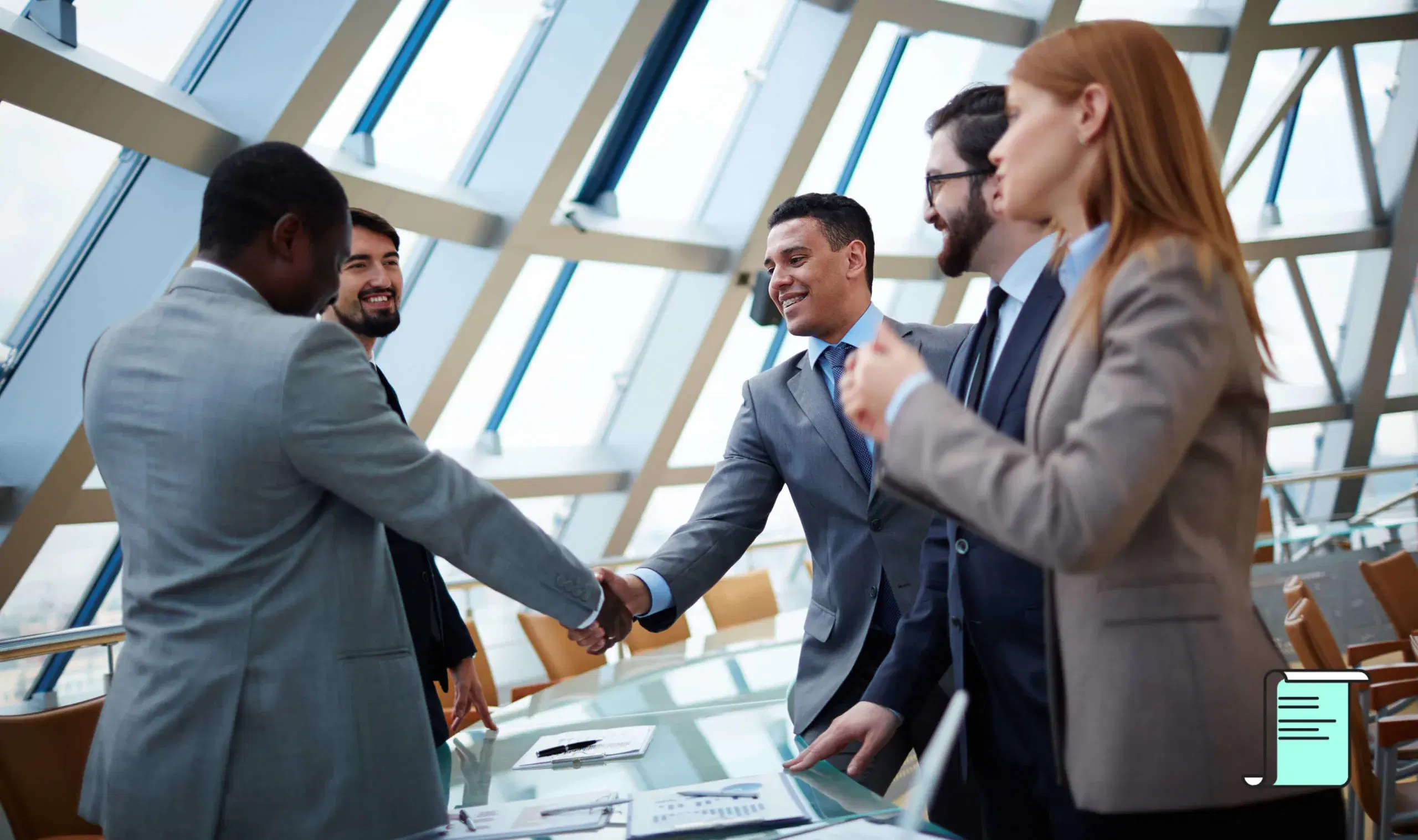 Business professionals shaking hands across a conference table in a modern office
