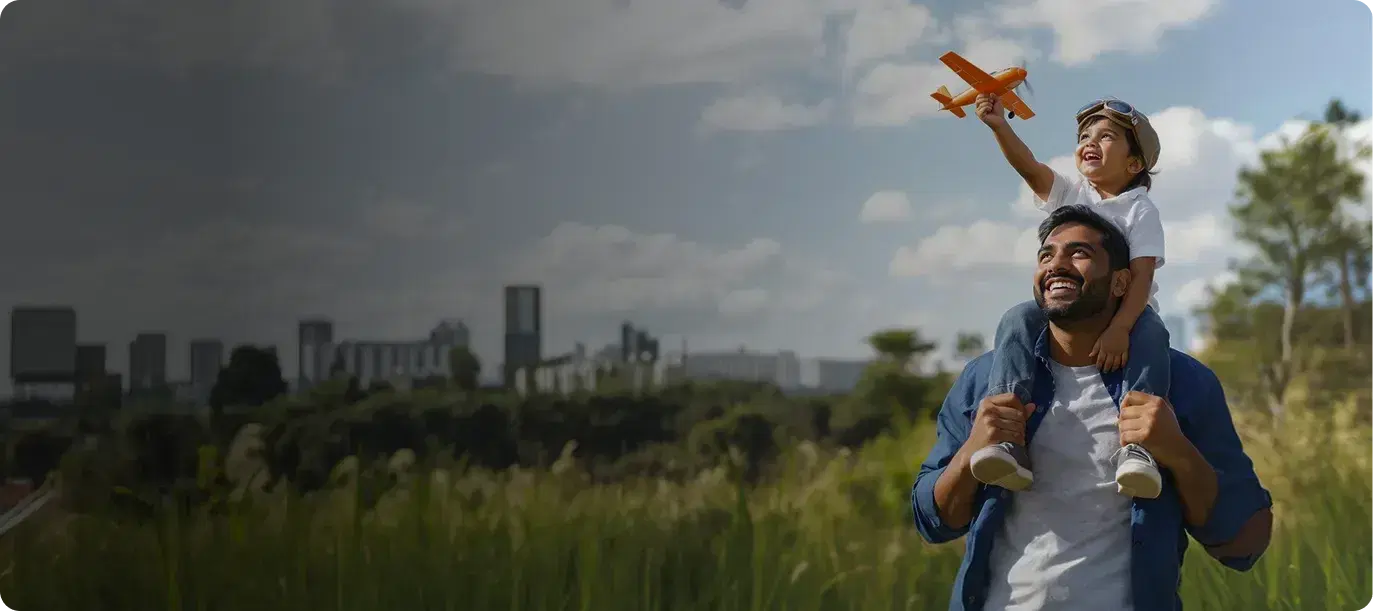 Father carrying his child on his shoulders as the child flies a toy plane
